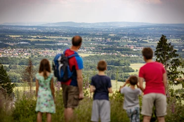 Wandern im Wiehengebirge Familie blickt von einem Aussichtspunkt im Wiehengebirge über das weite Tal.