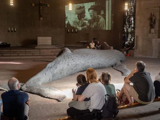 Opening at St. Gertrud for the exhibition GESTRANDET Visitors sit in front of a large whale sculpture at the GESTRANDET exhibition in St. Gertrud