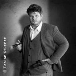 Schwarz-Weiß-Porträt von Jan Philipp Zymny im Anzug mit Pfeife und Kamera.