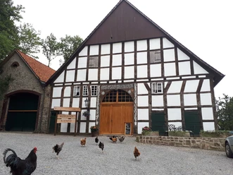 Fachwerkhaus des Hofladens Klemme mit Hühnern auf dem Kiesvorplatz.