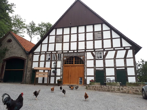 Fachwerkhaus des Hofladens Klemme mit Hühnern auf dem Kiesvorplatz.