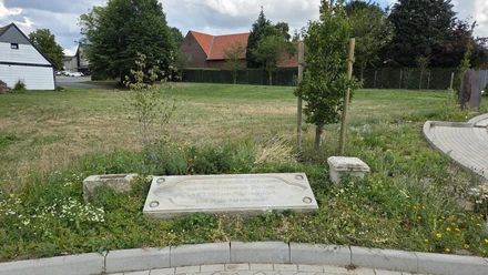 Firststein des Alten Pfarrhauses in einer bepflanzten Grünanlage in Hüllhorst.
