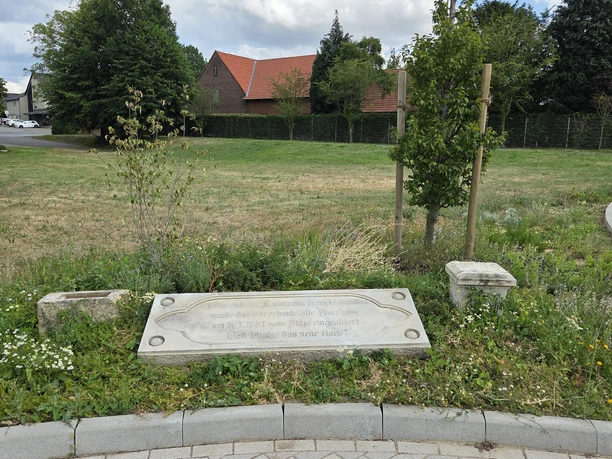 Firststein des Alten Pfarrhauses in einer bepflanzten Grünanlage in Hüllhorst.