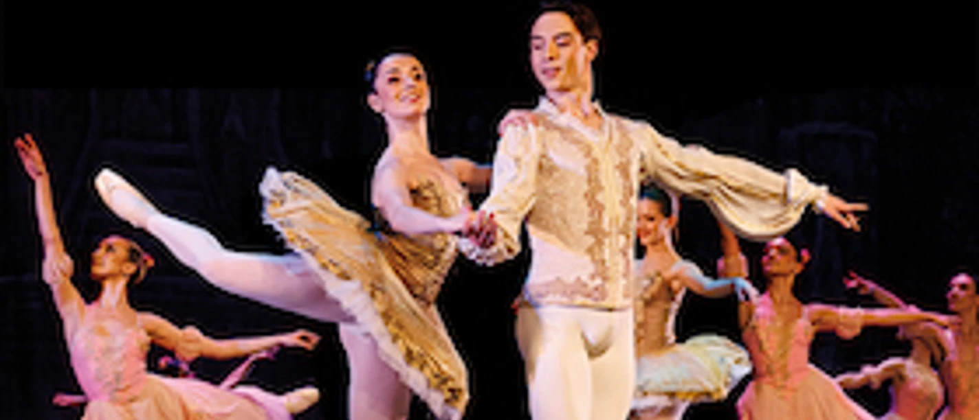 Ballettszene aus Der Nussknacker mit Tänzerinnen und Tänzer in festlichen Kostümen.