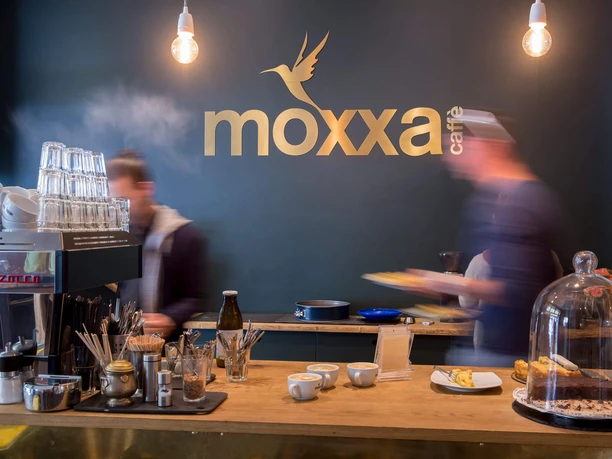 Theke im moxxa.caffè Theke der moxxa.caffè Rösterei mit Tassen, Kuchen und bewegten Baristas