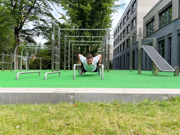 Trainingspark-Calisthenics-Park-Uebung.jpg Mann trainiert am Barren im Calisthenics-Park neben dem Reha-Zentrum am Meer.