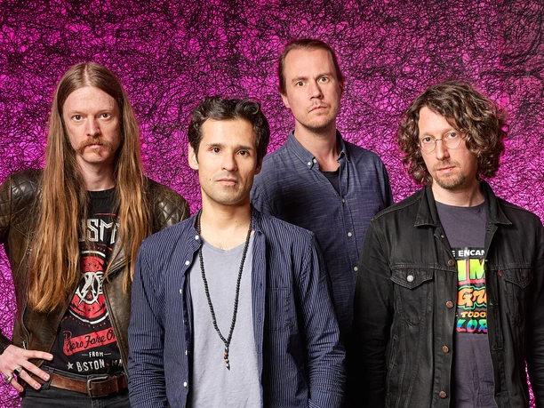 Four musicians from the band Jin Jim against a pink, graphically patterned background
