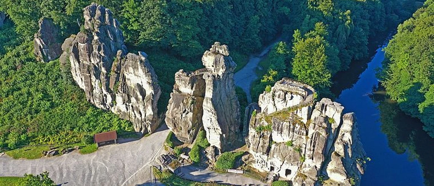 Luftaufnahme der Externsteine mit markanten Felsen, Wald und Wasserlauf