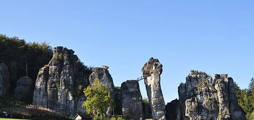 Felsformation der Externsteine mit Besuchern auf Aussichtsplattform bei klarem Himmel