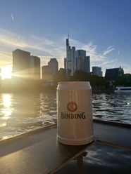 Binding-Bierkrug Bierkrug am Mainufer mit Skyline bei Sonnenuntergang