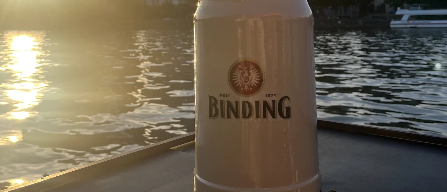 Binding-Bierkrug Bierkrug am Mainufer mit Skyline bei Sonnenuntergang