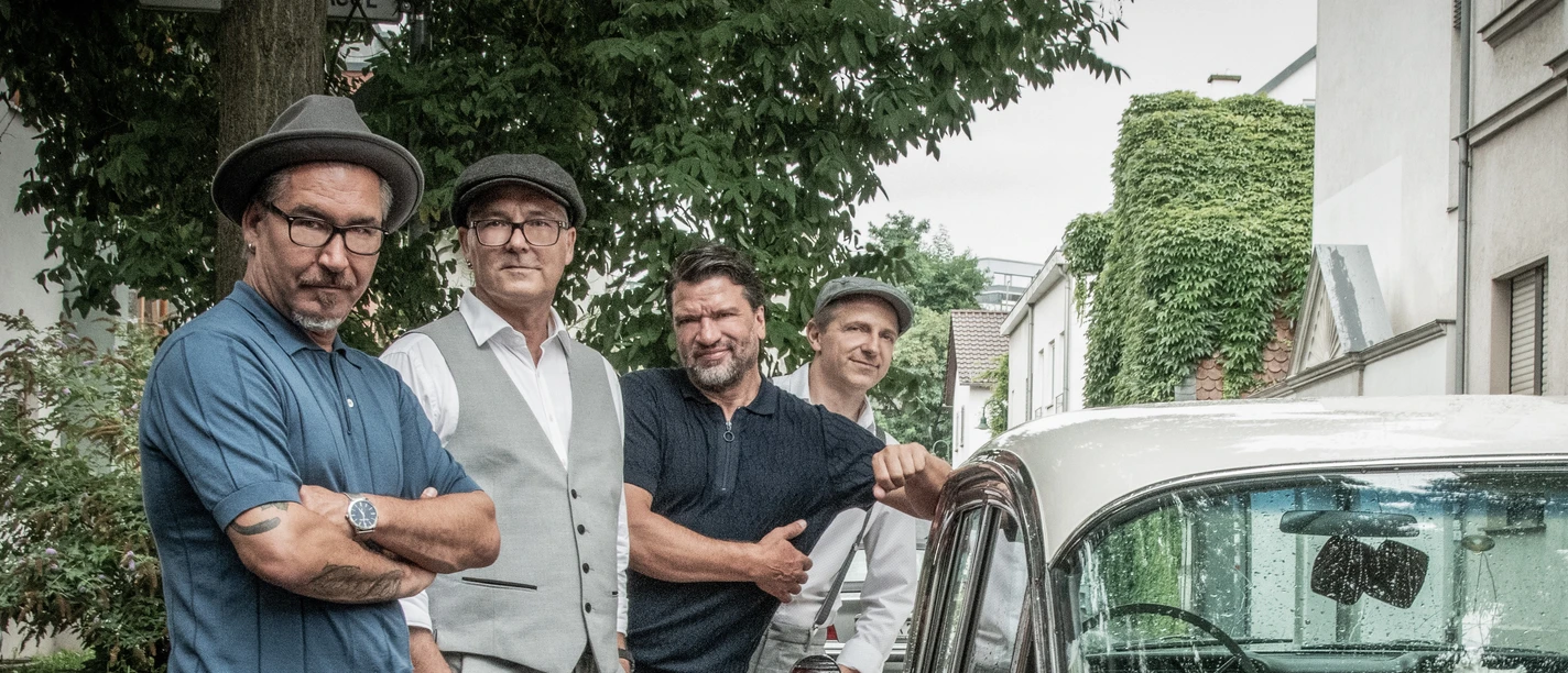 Silverballs Vier Männer neben rotem Oldtimer in Wohnstraße
