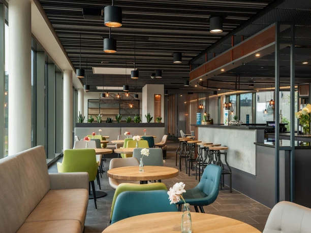 Saunagastronomie PiORAMA Moderner Gastronomiebereich im PiORAMA mit Bar, runden Tischen und farbigen Sesseln im Saunabereich