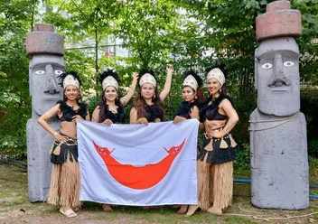 Pehuén e.V. Fünf Tänzerinnen mit Flagge zwischen Moai‑Statuen im Park