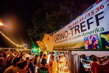 Fiesta Latina - Menschenmenge Menschen an Latino‑Stand bei Nachtfestival am Fluss