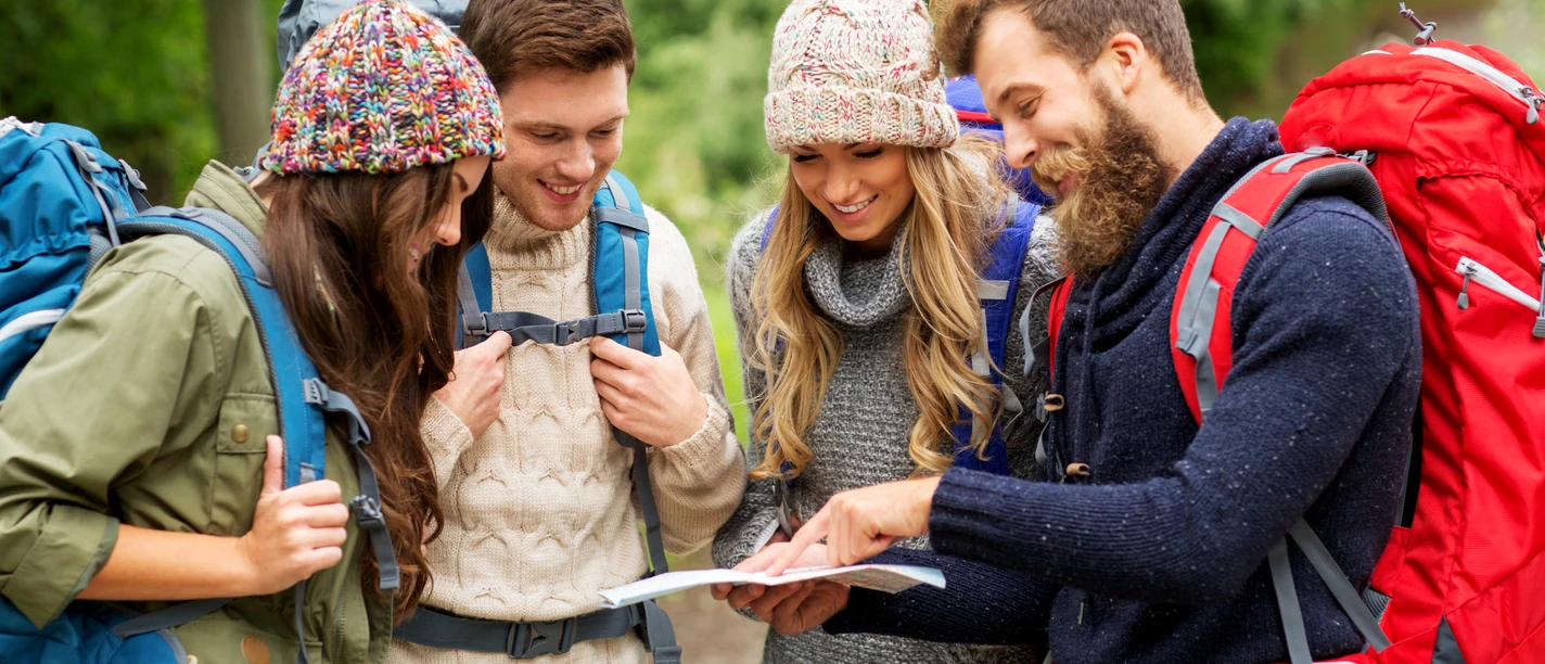 friends or travelers hiking with backpacks and map