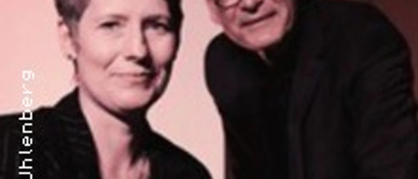 Porträt eines Musikerduos: Sängerin und Pianist vor warmem Hintergrund