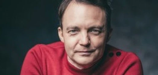 Porträt von Carsten Bender in rotem Pullover vor dunklem Hintergrund