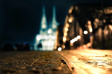 Hohenzollernbrücke bei Nacht Unscharfer Nachtblick von der Hohenzollernbrücke zum Kölner Dom, warmes Licht auf Pflaster