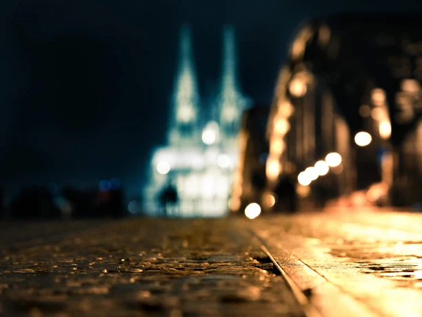 Hohenzollernbrücke bei Nacht Unscharfer Nachtblick von der Hohenzollernbrücke zum Kölner Dom, warmes Licht auf Pflaster