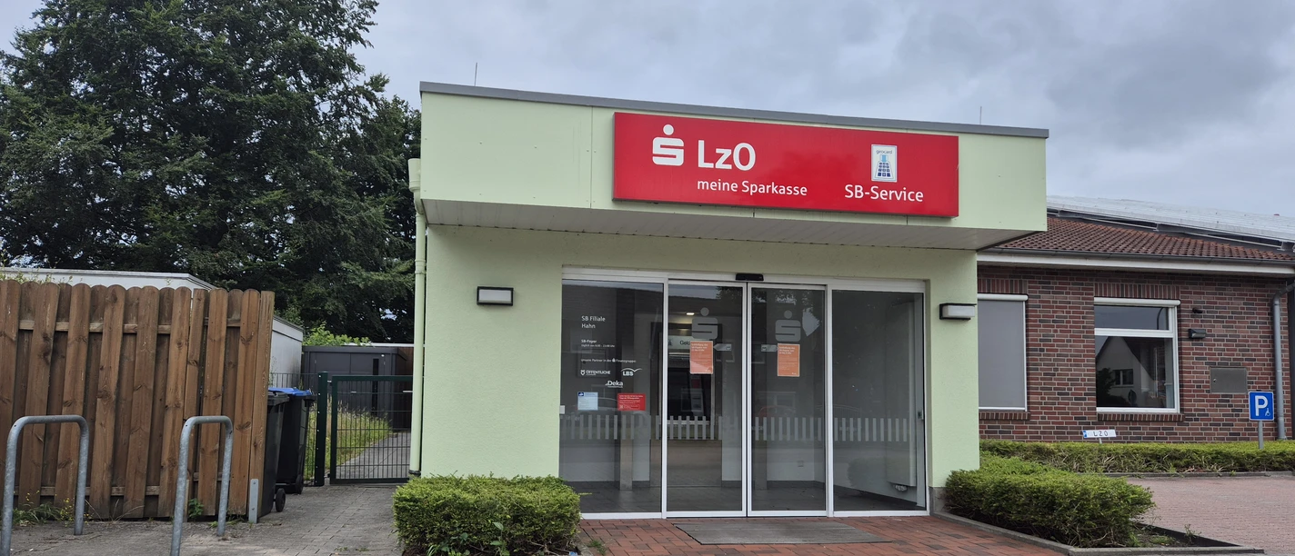 LzO SB-Filiale Außenansicht Eingang der LzO SB-Filiale Hahn mit rotem Schild, Glasfront und Parkplatz.