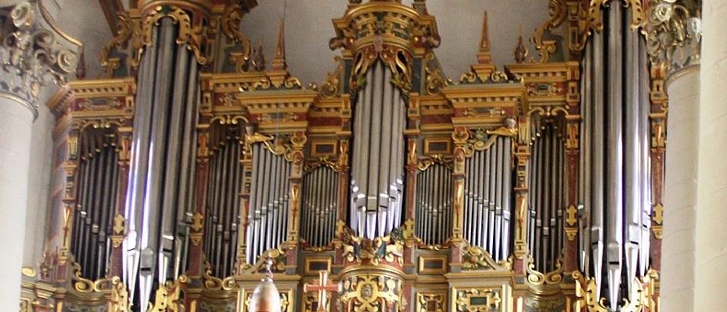 Prächtig verzierte Kirchenorgel mit goldenen Ornamenten und hohen silbernen Pfeifen
