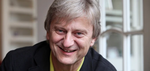 Porträt von Joachim Thalmann, lächelnd vor einem Fenster
