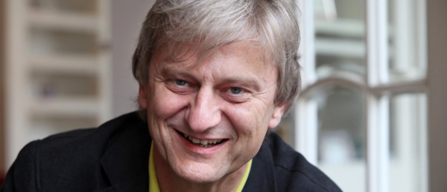 Porträt von Joachim Thalmann, lächelnd vor einem Fenster