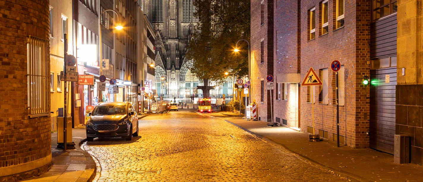 Blick auf den Kölner Dom Nächtlicher Blick durch eine Kölner Straße auf die beleuchteten Türme des Doms