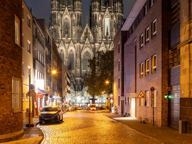 Blick auf den Kölner Dom Nächtlicher Blick durch eine Kölner Straße auf die beleuchteten Türme des Doms