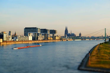 Kölner Rheinpanorama mit Kranhäusern, Dom, Severinsbrücke und Frachtschiff im Morgenlicht
