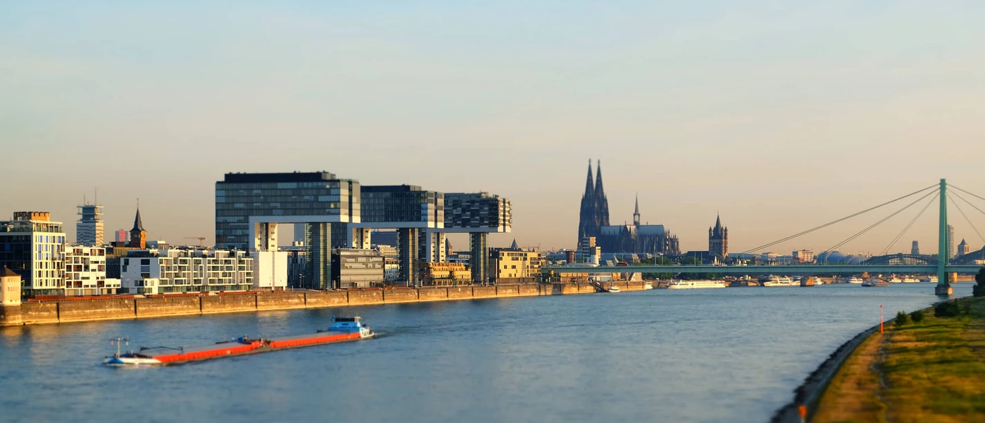 Kölner Rheinpanorama mit Kranhäusern, Dom, Severinsbrücke und Frachtschiff im Morgenlicht