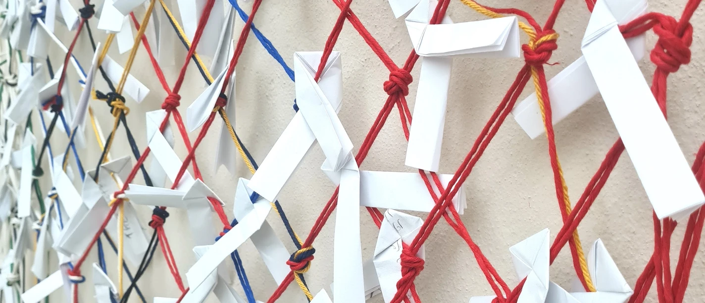 Knotenworkshop im Jüdischen Museum Frankfurt Papierobjekte an farbigen Schnüren in einer Ausstellung.