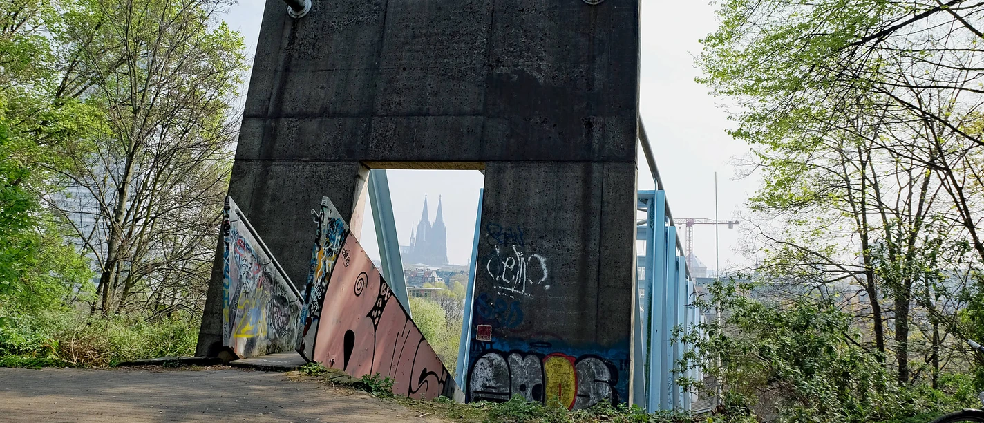 Betonbauwerk mit Graffiti am Herkulesberg, dahinter Blick auf den Kölner Dom