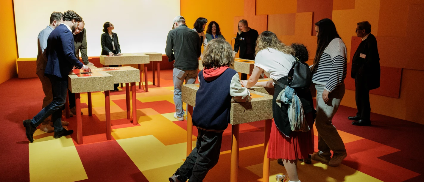 Workshop im Jüdischen Museum Frankfurt Besuchende in orangem Ausstellungsraum mit Stationen.