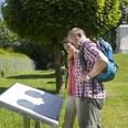 Löwendenkmal in Schierling/Eggmühl Zwei Personen betrachten eine Informationstafel vor dem Löwendenkmal im Grünen.