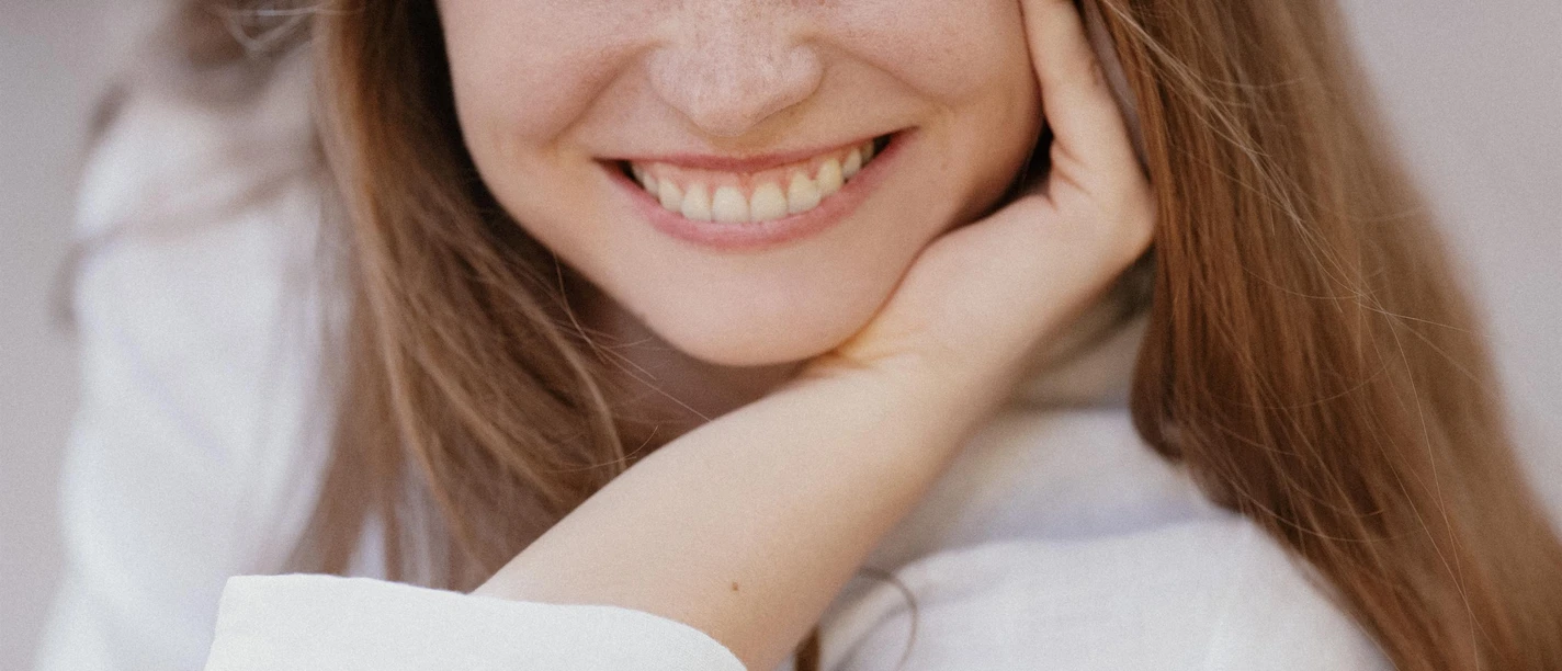Porträt von Izabele Jankauskaite, lächelnd in weißer Bluse mit Hand am Gesicht