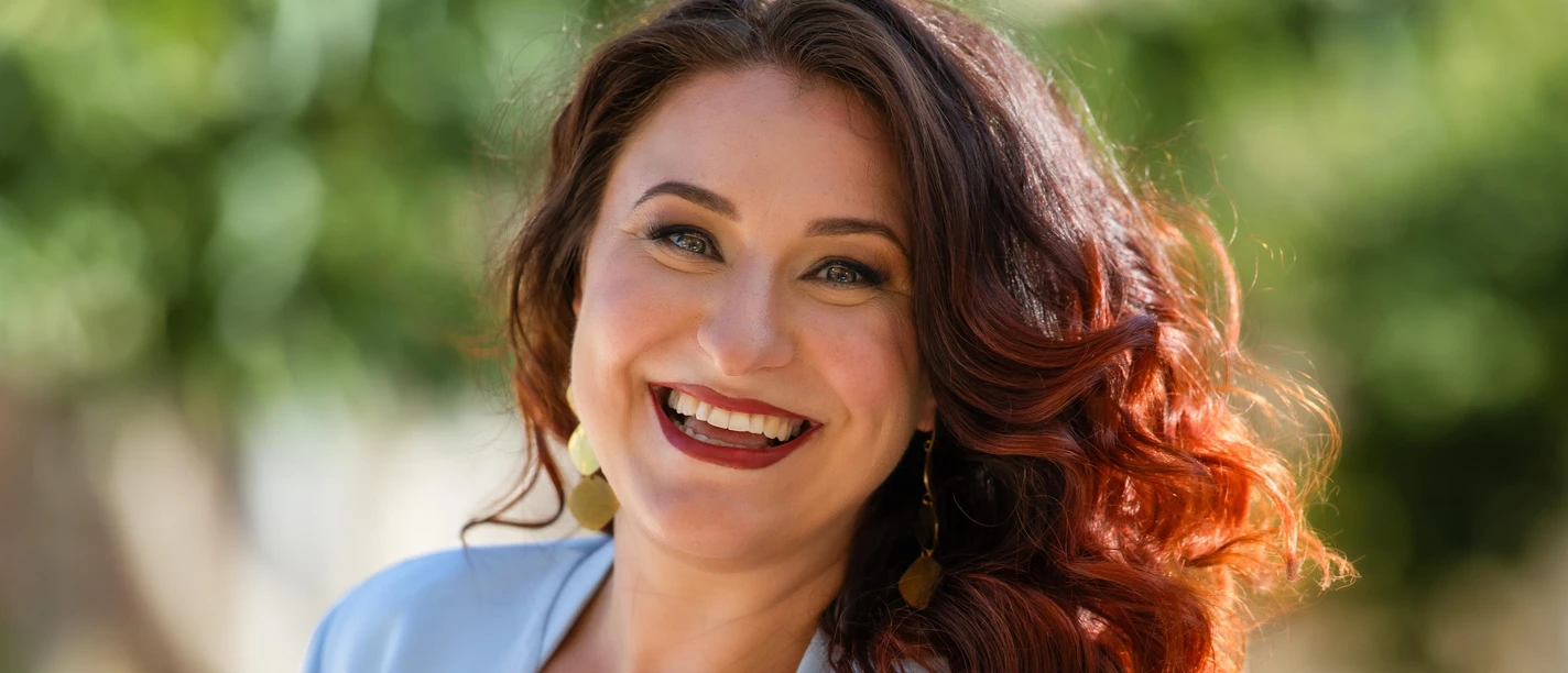 Porträt von Maryna Zubko, lächelnd vor unscharfem grünen Hintergrund