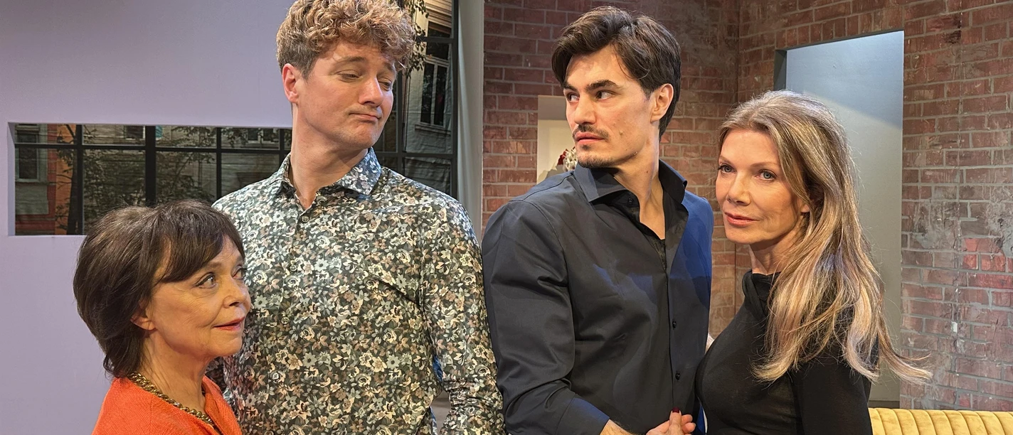 Vier Darsteller auf einer Theaterbühne vor Backsteinwand und gelbem Sofa