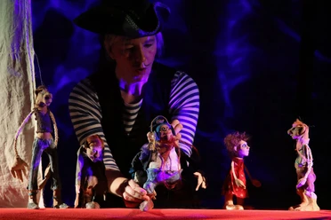 Puppentheater Puppenspielerin mit Figuren auf Bühne bei Theateraufführung