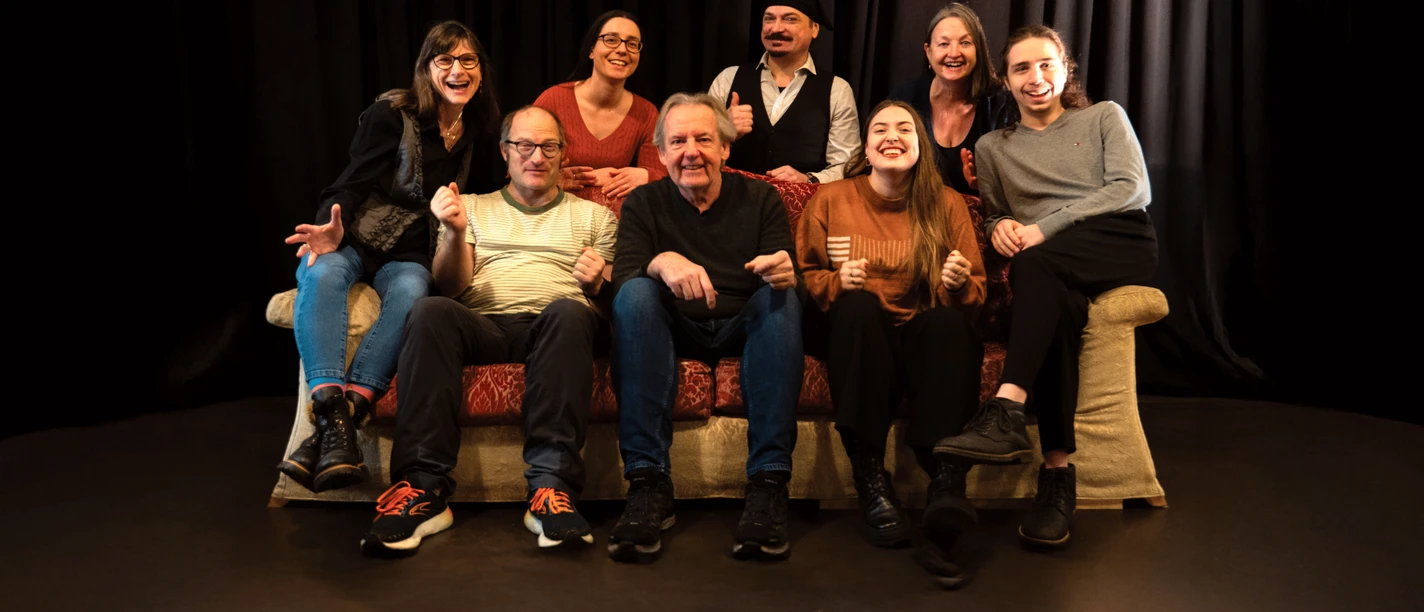 Wackerschnuppen Improvisationstheater Gruppe sitzt auf Sofa auf Theaterbühne vor Vorhang