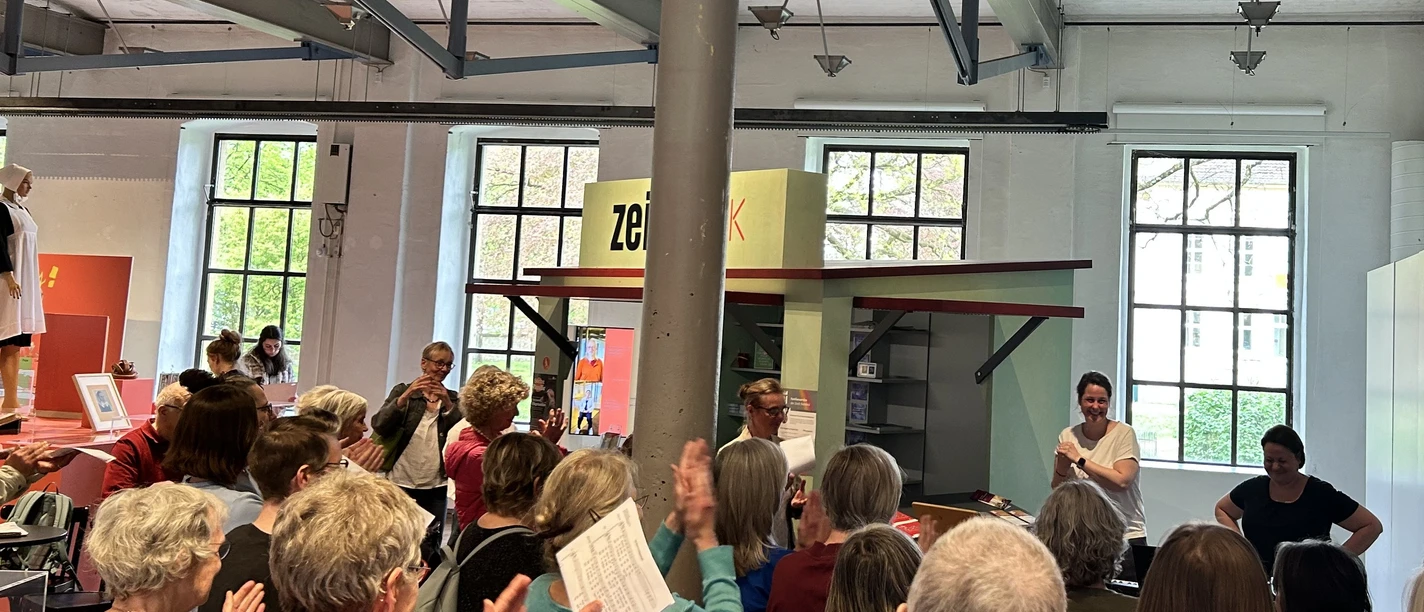 Das Bild zeigt Sängerinnen und Sänger, die mit Freude im Ausstellunsgraum des Museums singen.