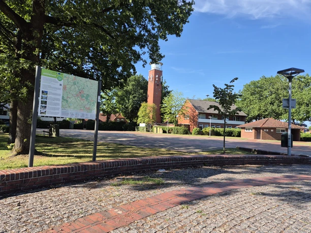 Knotenpunktübersichtskarte am Marktplatz Rastede mit Backsteinturm im Hintergrund.