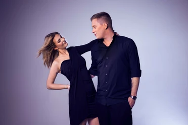 Straßenmusiker Julian Fiege An elegant couple dressed in black poses against a neutral background.