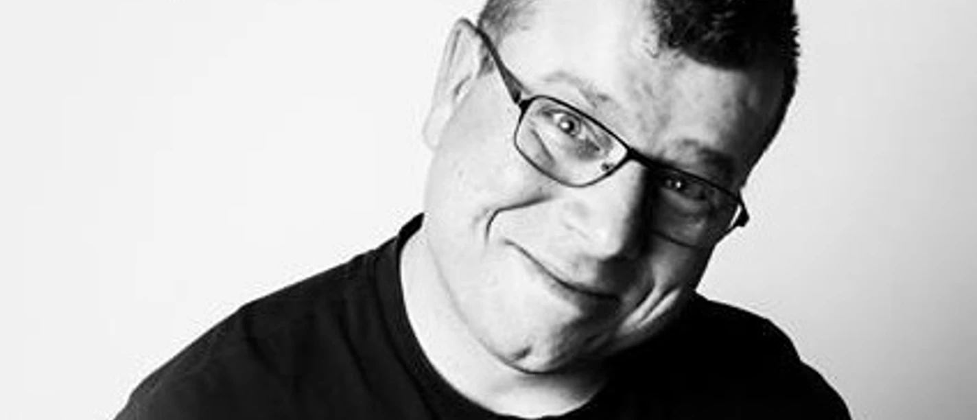 Ingo Margraf Mann in schwarzem T-Shirt und Brille lächelt in die Kamera, schwarz-weiß Foto.