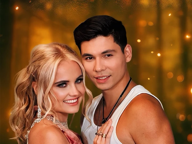 A smiling couple in festive attire against a sparkling, golden background.