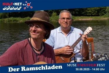 KULT-Net Bühne - DER RAMSCHLADEN Zwei Musiker von Der Ramschladen spielen Gitarre am See.