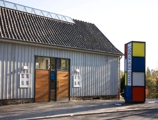 Eingang des Haus der Kunst in Nümbrecht mit Holzportal und farbiger Stele am Straßenrand