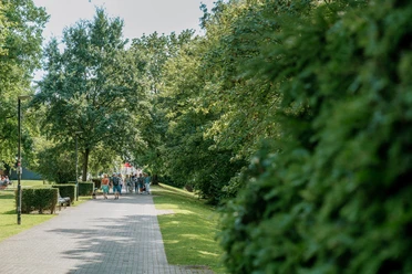 Sommerlicher Weg in den Ruhranlagen mit Spaziergängern, Bäumen und viel Grün
