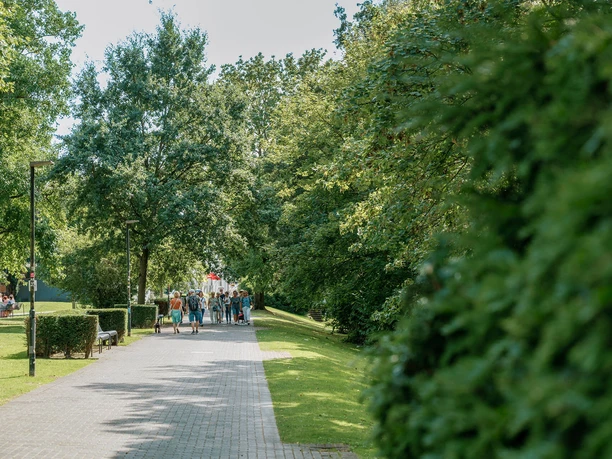 Sommerlicher Weg in den Ruhranlagen mit Spaziergängern, Bäumen und viel Grün